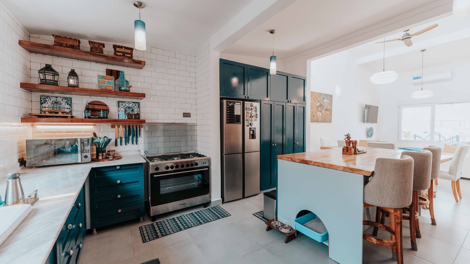 Modern kitchen with teal cabinets, wooden shelves, and kitchen island with pet area
