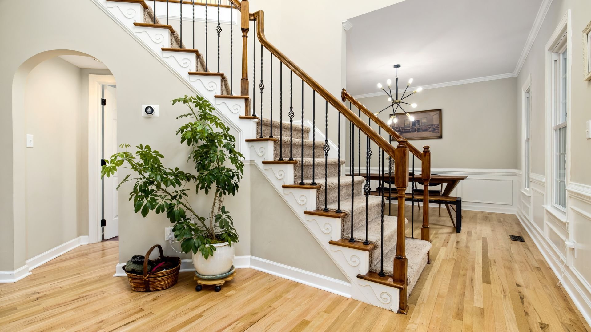 Elegant interior with wooden stairs, iron railings, and potted plant
