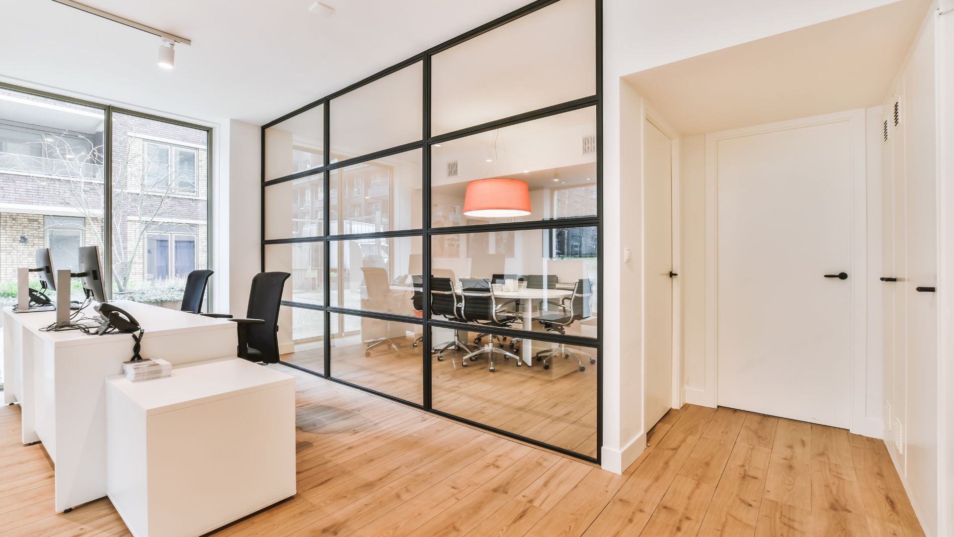Modern office with glass partition, wooden floors, and conference room